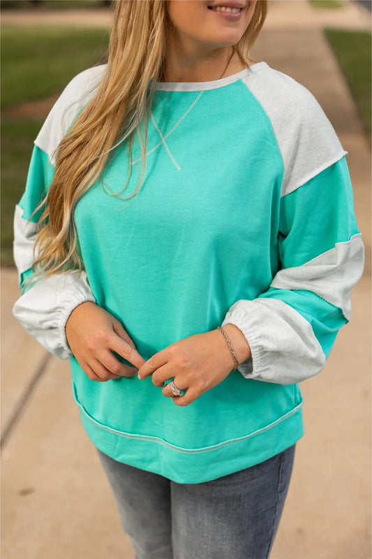 Front view of Plus Size Exposed Seam Color Block Long Sleeve Sweatshirt in Turquoise showing neckline and sleeve details